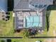 Top-down view of a screened-in pool area with outdoor seating, lush greenery, and surrounding fences at 2830 Dudley Ave, Odessa, FL 33556