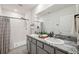 Bathroom featuring double sinks with granite countertops, a shower, and modern fixtures at 30845 Penny Surf Loop, Wesley Chapel, FL 33545