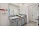 Bathroom featuring double sinks with granite countertops and modern fixtures, alongside a toilet and door at 30845 Penny Surf Loop, Wesley Chapel, FL 33545