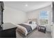 Well-lit bedroom with a comfortable bed, side table with a lamp, and a dresser at 30845 Penny Surf Loop, Wesley Chapel, FL 33545
