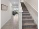 Inviting hallway featuring neutral tile flooring and carpeted stairs, leading into a cozy living area at 30845 Penny Surf Loop, Wesley Chapel, FL 33545
