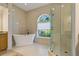 Luxurious bathroom with a standalone tub, glass shower, and a bright window with natural light at 370 Tall Oak Trl, Tarpon Springs, FL 34688