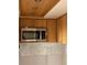 Kitchen area with oak cabinets, stainless steel microwave, and hexagon tile backsplash at 4712 Marine Pkwy # 104, New Port Richey, FL 34652