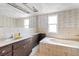 Bright bathroom featuring a soaking tub, neutral tile, wallpaper, and vanity at 5441 Alderwood St, Spring Hill, FL 34606