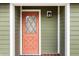 Close-up of a front door boasting a unique diamond-patterned window and a fresh coat of salmon paint at 5441 Alderwood St, Spring Hill, FL 34606