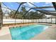 Beautiful screened-in pool with clear water, surrounded by a spacious patio and complemented by a well-maintained fence at 5441 Alderwood St, Spring Hill, FL 34606