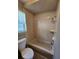 Bathroom featuring a tile shower/tub combo with tiled walls, a toilet, and a window at 7028 Merrick Ln, Spring Hill, FL 34606