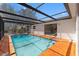 The screened-in pool features an orange concrete deck and easy access to sliding glass doors to the home's interior at 7048 Oberon Ave, Spring Hill, FL 34608