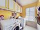 Bright laundry room featuring a washing machine, dryer, overhead cabinets, and a window with natural light at 7912 Trail Run Loop, New Port Richey, FL 34653