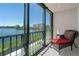 Balcony with a scenic view of a lake and a comfortable wicker chair with a red cushion at 8211 Brent St # 816, Port Richey, FL 34668