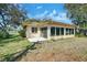 Backyard view showcasing the home's sunroom addition with a concrete patio at 8420 Winding Wood Dr, Port Richey, FL 34668