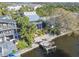 Waterfront home featuring a metal roof, screened balcony, lush landscaping, and a private boat lift at 8721 Old Post Rd, Port Richey, FL 34668