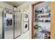 Well-organized pantry with stainless steel refrigerator and stacked washer/dryer for added convenience at 8721 Old Post Rd, Port Richey, FL 34668