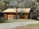 Wooden barn's exterior with wood fence and carport, surrounded by natural landscaping on the property at 9382 Wild Horse Trl, Brooksville, FL 34601