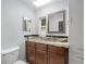 Well-lit bathroom with granite countertop, decorative mirror, and storage cabinet at 9382 Wild Horse Trl, Brooksville, FL 34601