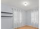 Bright bedroom featuring hardwood floors, neutral paint, two large windows with white curtains and black shelves at 9382 Wild Horse Trl, Brooksville, FL 34601