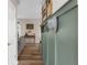 Hallway with views into the living room featuring green wainscotting and wood flooring at 11227 Lakeview Dr, New Port Richey, FL 34654