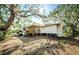 An exterior, rear view of the home shows a spacious backyard and porch, surrounded by trees at 120 Read St, Tarpon Springs, FL 34689