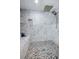 This is the shower with a stone floor, marble styled tiles, and a built-in shampoo shelf at 120 Read St, Tarpon Springs, FL 34689