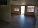 Open-concept living room featuring tile floors, neutral paint, and natural light from windows and a glass door at 12716 Mulberry Ln, Hudson, FL 34667