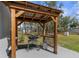 Outdoor kitchen with grill and counter space under a wooden pergola in a grassy backyard at 13414 English Parrot Rd, Brooksville, FL 34614