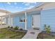 The exterior showcases a light-blue home with a covered entry, small bushes, and well-maintained lawn at 13604 Maria Dr, Hudson, FL 34667