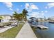 Waterfront view showcasing a dock with boat lift, tropical landscaping, and canal-front living at 13604 Maria Dr, Hudson, FL 34667