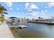 Waterfront showcasing a dock with boat lift, tropical landscaping, and canal-front living at 13604 Maria Dr, Hudson, FL 34667
