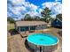 Aerial view of the backyard featuring a pool, wooden deck, a screened in porch and mature trees at 2165 Bolger Ave, Spring Hill, FL 34609