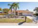 Charming single-story home with a well-manicured lawn, rock garden, palm trees, and a three-car garage at 2224 Sand Bay Dr, Holiday, FL 34691