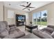 Cozy living room with plush seating, media center, ceiling fan, and sliding glass doors to view the backyard at 2330 Tarragon Ln, Trinity, FL 34655