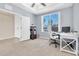 This home office is brightly lit with neutral walls, tan carpet and a window with a view of the neighborhood at 2330 Tarragon Ln, Trinity, FL 34655