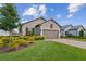 Attractive home showcasing a lush green lawn, complemented by colorful landscaping and a brick paver driveway leading to a two-car garage at 4142 Montegrappa Way, Wesley Chapel, FL 33543