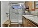 Bathroom featuring a marble tiled shower with a glass door and natural wood cabinets at 4560 Lamson Ave, Spring Hill, FL 34608