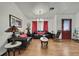 Cozy living room featuring dark leather sofas, a decorative chandelier, and a striking red entry door at 4560 Lamson Ave, Spring Hill, FL 34608