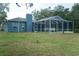 Spacious backyard with screened-in pool, grassy lawn, and views of the home's exterior at 6393 Pinehurst Dr, Spring Hill, FL 34606