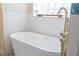 Bright bathroom showcasing a modern white freestanding tub with gold hardware and glass block window at 6393 Pinehurst Dr, Spring Hill, FL 34606
