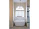 A white stand-alone tub next to a window in a bathroom with earth-tone colored walls and tile floors at 6393 Pinehurst Dr, Spring Hill, FL 34606