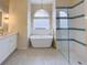 This bathroom showcases a step-in shower with a sleek glass enclosure, soaking tub, and modern vanity at 6393 Pinehurst Dr, Spring Hill, FL 34606