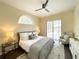 Bright bedroom featuring a comfortable bed, large arched window, and view to backyard pool at 6393 Pinehurst Dr, Spring Hill, FL 34606