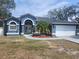 Charming blue single-story home featuring a two-car garage, arched entryway, and well-maintained landscaping at 6393 Pinehurst Dr, Spring Hill, FL 34606