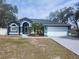 Charming blue single-story home with well-manicured landscaping, arched entry, and a two-car garage at 6393 Pinehurst Dr, Spring Hill, FL 34606