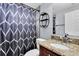 Stylish bathroom with granite vanity top, decorative mirror shelves, and shower with patterned curtain at 7037 Green St, New Port Richey, FL 34652