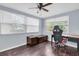 Bedroom featuring a ceiling fan, hardwood floors, multiple windows, desk and an ergonomic gaming chair at 7037 Green St, New Port Richey, FL 34652