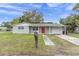 Charming single-story home with a manicured lawn and an inviting red front door at 7037 Green St, New Port Richey, FL 34652