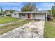 Cozy home featuring a one-car garage, long driveway, and vibrant red front door at 7037 Green St, New Port Richey, FL 34652