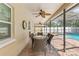 Covered patio with ceiling fans, brick floor, and outdoor dining set, overlooking the sparkling pool at 8017 Shepherd Ave, Spring Hill, FL 34606