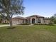 Exterior of home featuring a well-kept lawn, brick walkway, and mature tree at 8373 Maybelle Dr, Weeki Wachee, FL 34613