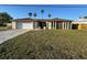 Charming single-story home featuring a two-car garage, stone accents, and a spacious front yard with palm trees at 8607 Longboat Ln, Hudson, FL 34667
