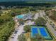 Aerial view showcases the pool, tennis courts, and surrounding greenery at 9634 Green Needle Dr, New Port Richey, FL 34655